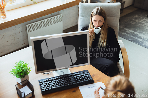 Image of Young woman sitting in office during the job interview with female employee, boss or HR-manager, talking, thinking, looks confident