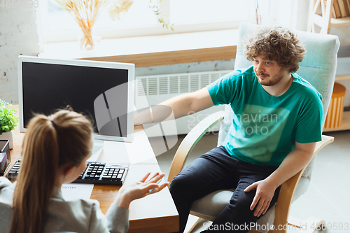 Image of Young man sitting in office during the job interview with female employee, boss or HR-manager, talking, thinking, looks confident