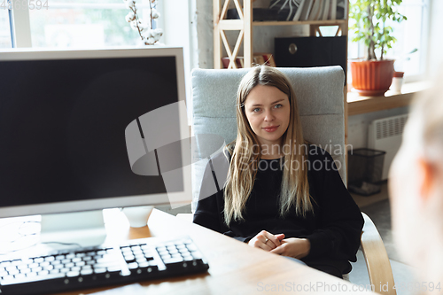 Image of Young woman sitting in office during the job interview with female employee, boss or HR-manager, talking, thinking, looks confident