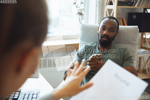 Image of Young man sitting in office during the job interview with female employee, boss or HR-manager, talking, thinking, looks confident