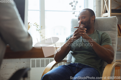 Image of Young man sitting in office during the job interview with female employee, boss or HR-manager, talking, thinking, looks confident