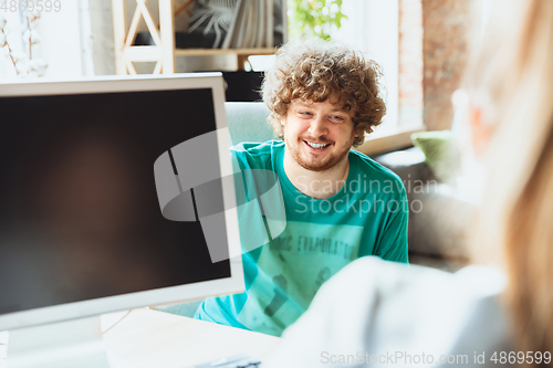 Image of Young man sitting in office during the job interview with female employee, boss or HR-manager, talking, thinking, looks confident