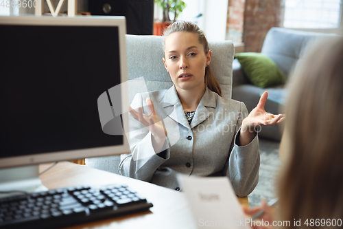 Image of Young woman in suit sitting in office during the job interview with female employee, boss or HR-manager, talking, thinking, looks confident