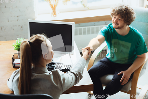 Image of Young man sitting in office during the job interview with female employee, boss or HR-manager, talking, thinking, looks confident