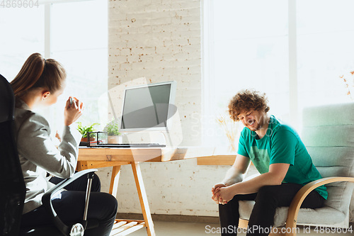 Image of Young man sitting in office during the job interview with female employee, boss or HR-manager, talking, thinking, looks confident