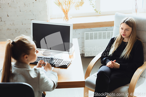 Image of Young woman sitting in office during the job interview with female employee, boss or HR-manager, talking, thinking, looks confident