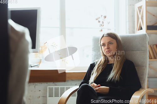 Image of Young woman sitting in office during the job interview with female employee, boss or HR-manager, talking, thinking, looks confident