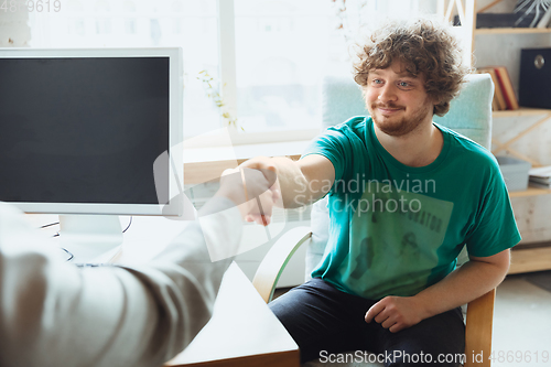 Image of Young man sitting in office during the job interview with female employee, boss or HR-manager, talking, thinking, looks confident