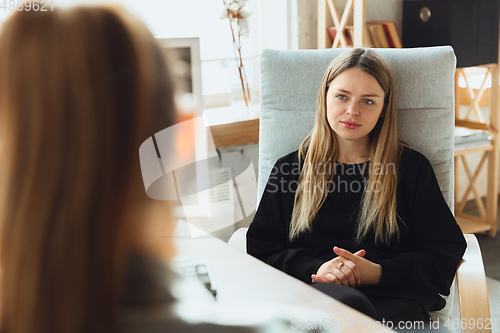 Image of Young woman sitting in office during the job interview with female employee, boss or HR-manager, talking, thinking, looks confident