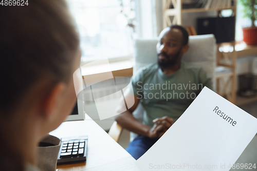 Image of Young man sitting in office during the job interview with female employee, boss or HR-manager, talking, thinking, looks confident