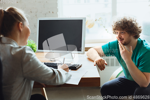 Image of Young man sitting in office during the job interview with female employee, boss or HR-manager, talking, thinking, looks confident