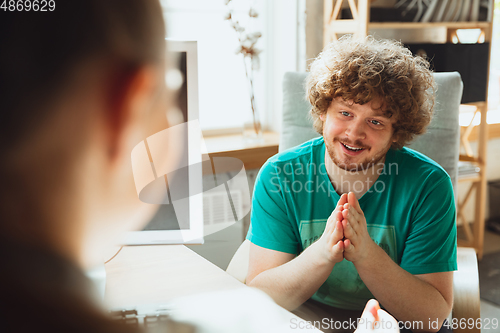 Image of Young man sitting in office during the job interview with female employee, boss or HR-manager, talking, thinking, looks confident