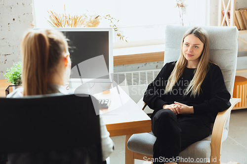 Image of Young woman sitting in office during the job interview with female employee, boss or HR-manager, talking, thinking, looks confident