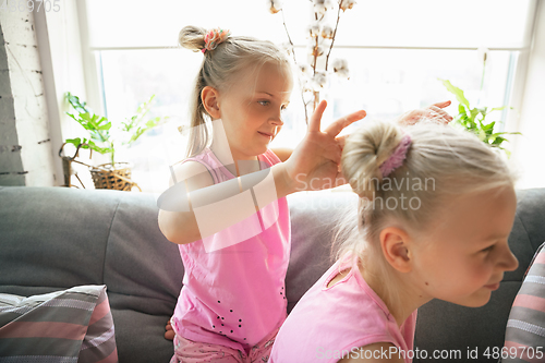 Image of Quiet little girls playing in a bedroom in cute pajamas, home style and comfort, making a hairstyle