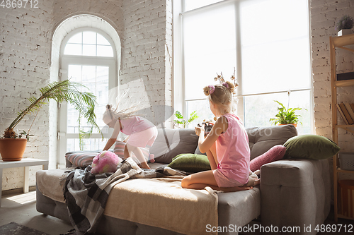 Image of Quiet little girls playing in a bedroom in cute pajamas, home style and comfort, taking a photo, having fun