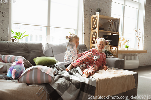 Image of Quiet little girls playing in a bedroom in cute pajamas, home style and comfort, laughting and fighting pillows