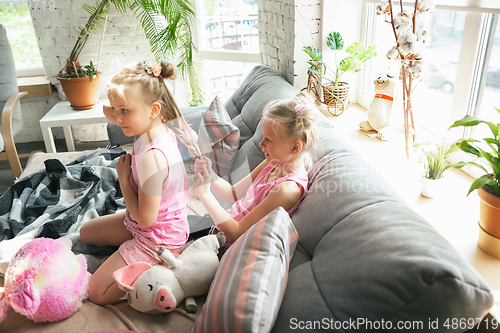 Image of Quiet little girls playing in a bedroom in cute pajamas, home style and comfort, making a hairstyle