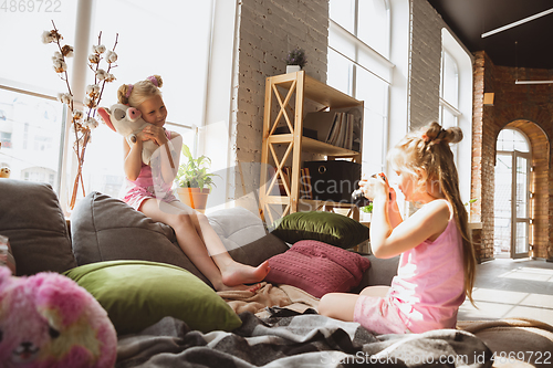 Image of Quiet little girls playing in a bedroom in cute pajamas, home style and comfort, taking a photo