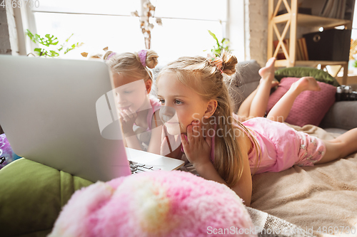 Image of Quiet little girls playing in a bedroom in cute pajamas, home style and comfort, watching cartoons, cinema, having fun