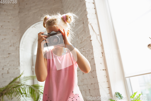 Image of Little girl playing in a bedroom in cute pajama, home style and comfort, taking a photo, having fun