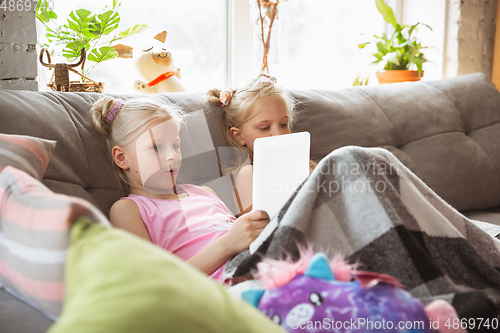 Image of Quiet little girls playing in a bedroom in cute pajamas, home style and comfort, watching cartoons, cinema, having fun