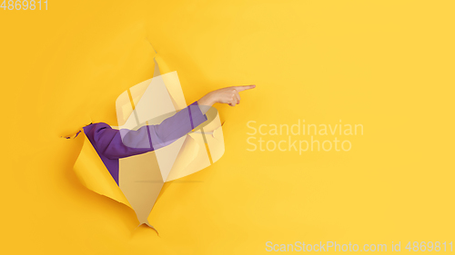 Image of Female hand gesturing in torn yellow paper hole background, flyer with copyspace