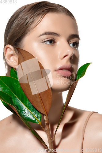 Image of Youth. Close up of beautiful young woman with green leaves on her face over white background. Cosmetics and makeup, natural and eco treatment, skin care
