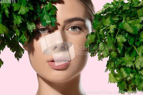 Image of Fresh. Close up of beautiful young woman with green leaves on her face over white background. Cosmetics and makeup, natural and eco treatment, skin care