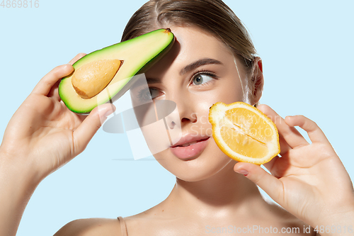 Image of Summer. Close up of beautiful young woman with fresh lemon and avocado over white background. Cosmetics and makeup, natural and eco treatment, skin care
