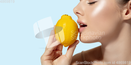 Image of Close up of beautiful young woman with fresh lemon over white background. Cosmetics and makeup, natural and eco treatment, skin care. Flyer with copyspace.