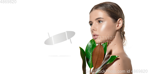 Image of Close up of beautiful young woman with green leaves on her face over white background. Cosmetics and makeup, natural and eco treatment, skin care. Flyer with copyspace.