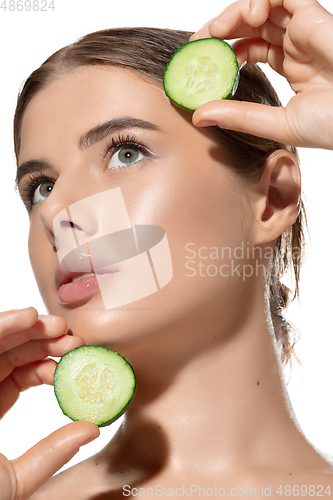 Image of Green. Close up of beautiful young woman with fresh cucumber slices over white background. Cosmetics and makeup, natural and eco treatment, skin care