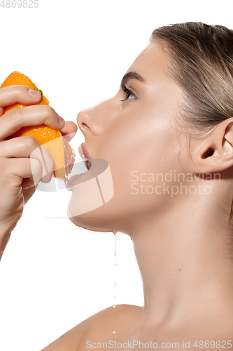 Image of Vitamins. Close up of beautiful young woman with fresh orange juice pouring over white background. Cosmetics and makeup, natural and eco treatment, skin care