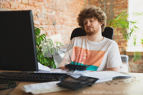 Image of Caucasian upset and despair man doing financial and economical reports with income going down during coronavirus quarantine, problems