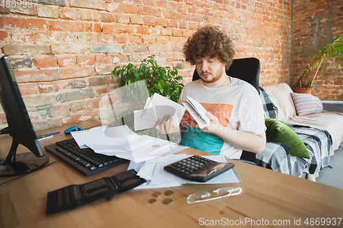 Image of Caucasian upset and despair man doing financial and economical reports with income going down during coronavirus quarantine, problems