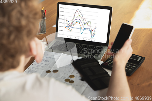 Image of Close up caucasian upset and despair man doing financial and economical reports with income graphs going down during coronavirus quarantine, problems, empty wallet