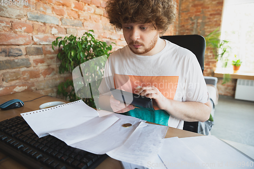 Image of Caucasian upset and despair man doing financial and economical reports with income going down during coronavirus quarantine, problems