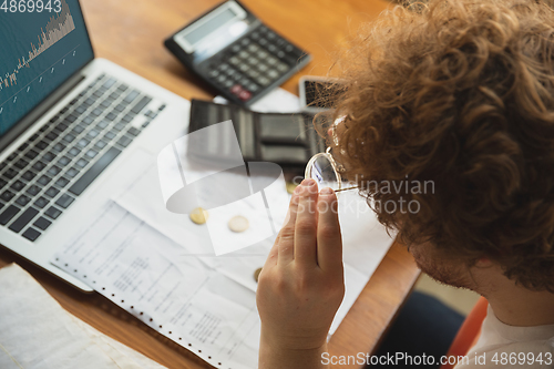 Image of Close up caucasian upset and despair man doing financial and economical reports with income graphs going down during coronavirus quarantine, problems, empty wallet