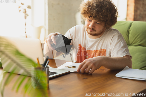 Image of Caucasian upset and despair man looking in empty wallet during coronavirus quarantine, business fall, lack of money, problems