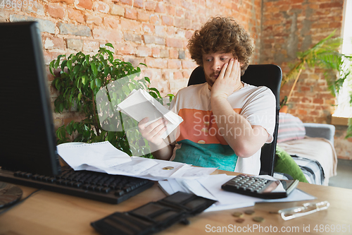 Image of Caucasian upset and despair man doing financial and economical reports with income going down during coronavirus quarantine, problems