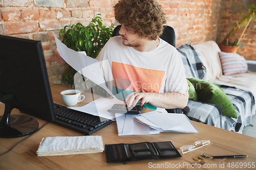 Image of Caucasian upset and despair man doing financial and economical reports with income going down during coronavirus quarantine, problems