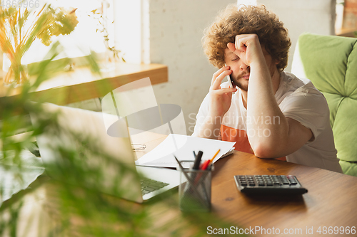 Image of Caucasian upset and despair man watching financial and economical reports with income graphs going down during coronavirus quarantine. Problems, empty wallet