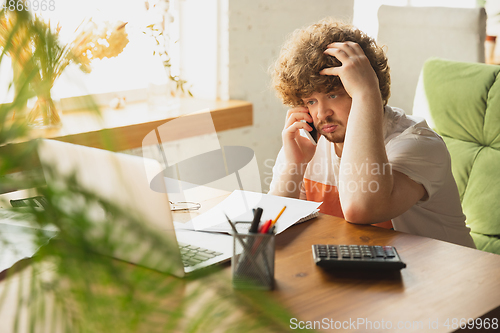 Image of Caucasian upset and despair man watching financial and economical reports with income graphs going down during coronavirus quarantine. Problems, empty wallet