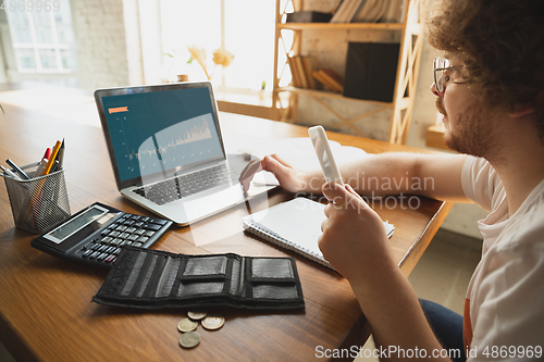 Image of Caucasian upset and despair man watching financial and economical graphs going down during coronavirus quarantine, problems