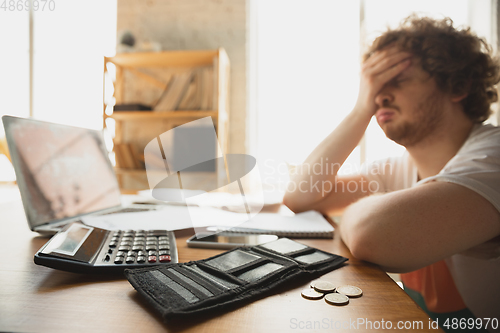 Image of Caucasian upset and despair man watching financial and economical graphs going down during coronavirus quarantine, problems