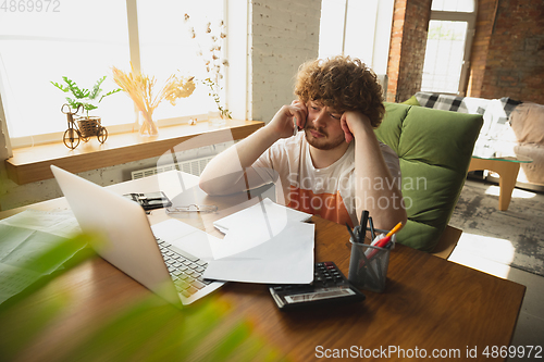 Image of Caucasian upset and despair man watching financial and economical reports with income graphs going down during coronavirus quarantine. Problems, empty wallet