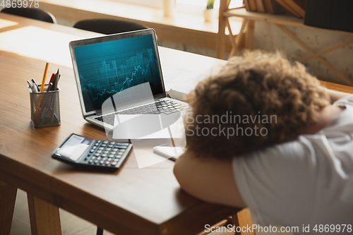 Image of Caucasian upset and despair man watching financial and economical graphs going down during coronavirus quarantine, problems