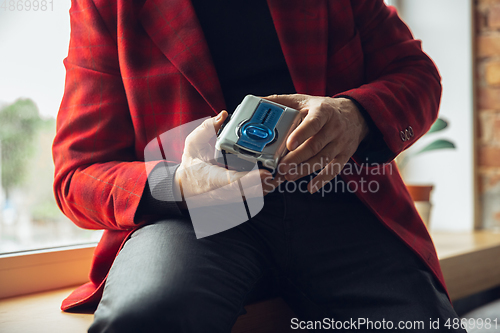 Image of Close up of senior man with retro toys, meeting things from the past and having fun, exploring the lifestyle of the nineties, using cassette player