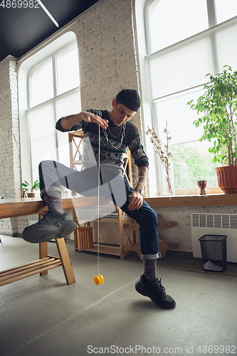 Image of Portrait of millenial boy using retro toys, meeting things from the past and having fun, exploring yo-yo game