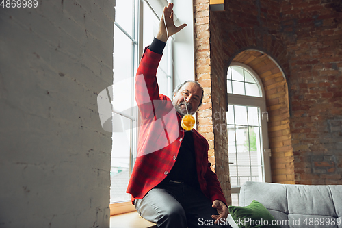 Image of Portrait of senior man with retro toys, meeting things from the past and having fun, exploring the lifestyle of the nineties, playing with yo-yo